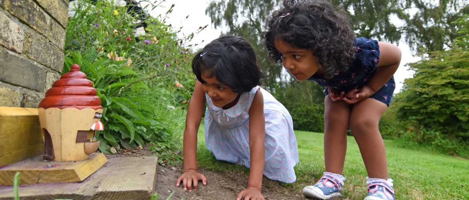 Two children looking at a fairy house at Furzey Gardens